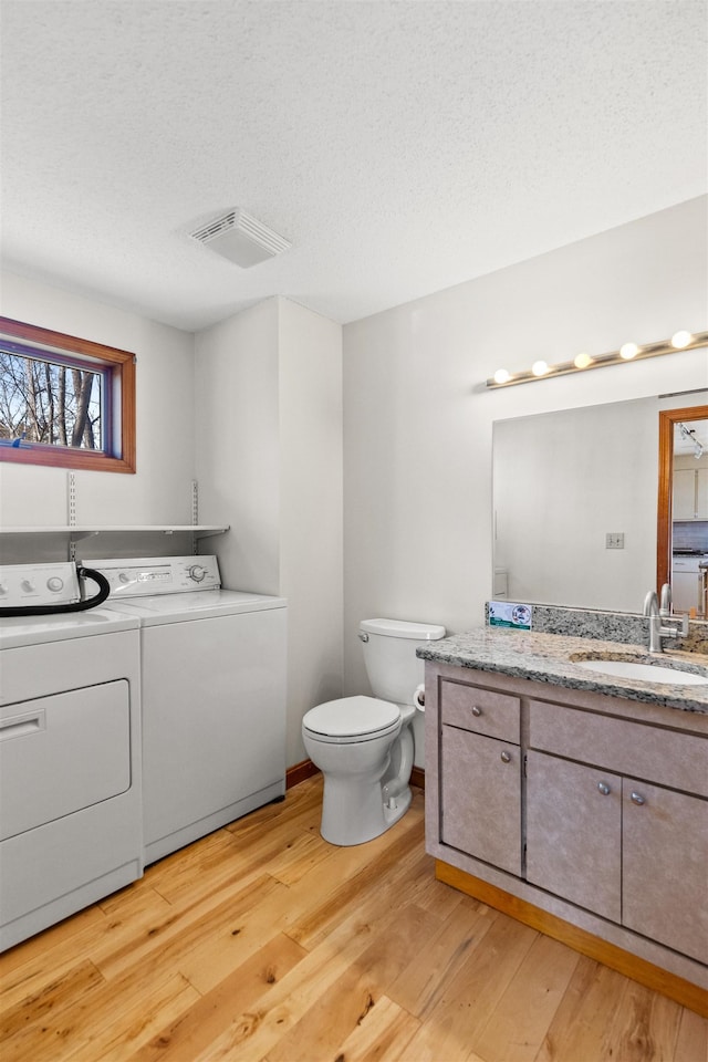 bathroom featuring a textured ceiling, visible vents, washer and dryer, wood finished floors, and vanity