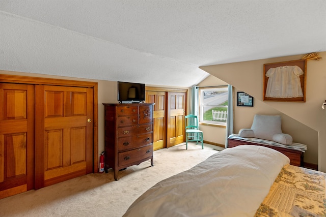 bedroom featuring light colored carpet, lofted ceiling, and a textured ceiling