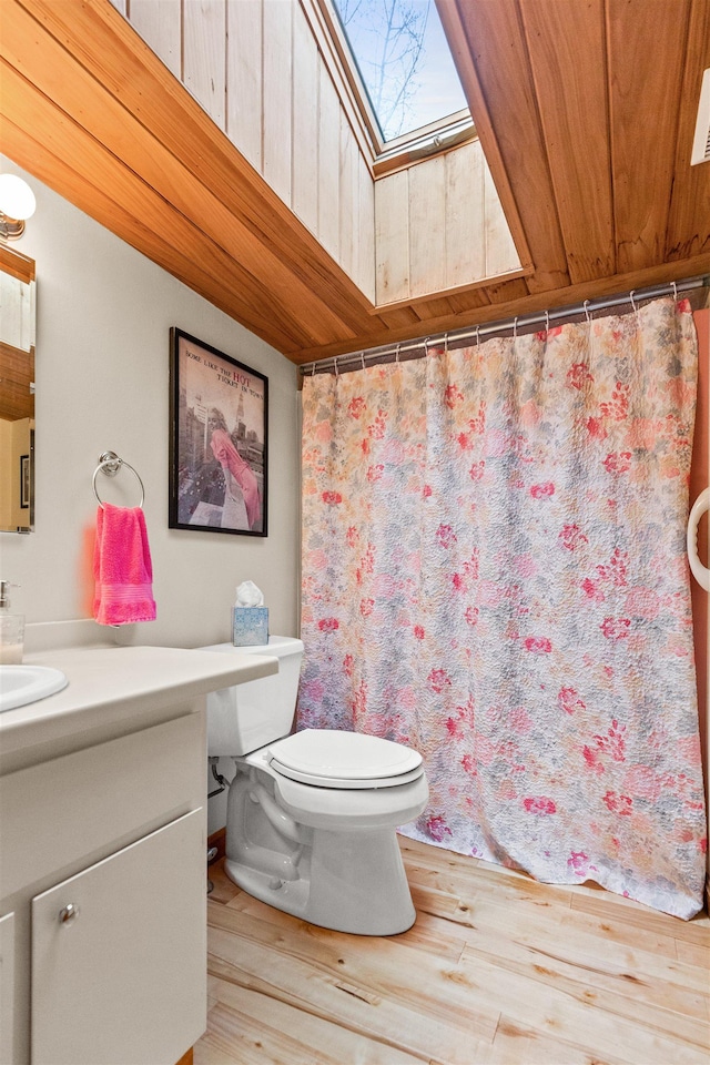 full bath featuring a shower with curtain, vanity, toilet, a skylight, and wood finished floors