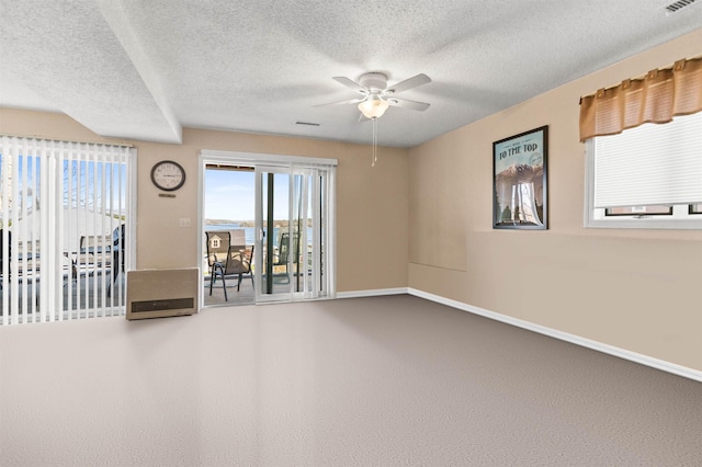 empty room featuring a textured ceiling, plenty of natural light, a ceiling fan, and baseboards