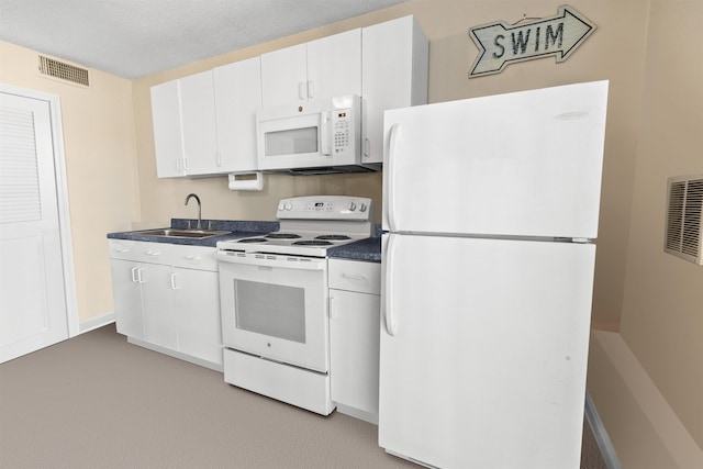 kitchen with white appliances, white cabinets, dark countertops, a sink, and visible vents