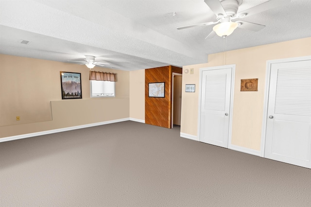 unfurnished room with visible vents, ceiling fan, dark carpet, and baseboards