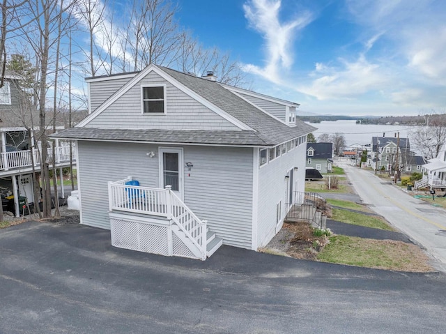 view of front of home with a water view and a shingled roof