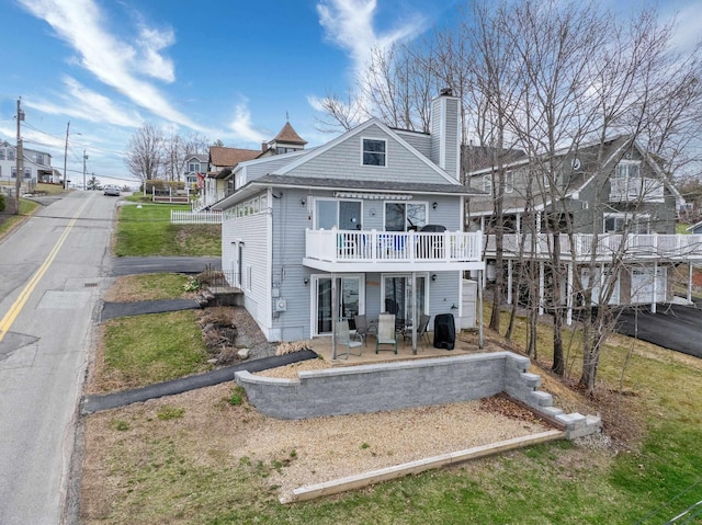 rear view of property featuring a deck, a patio area, and a chimney