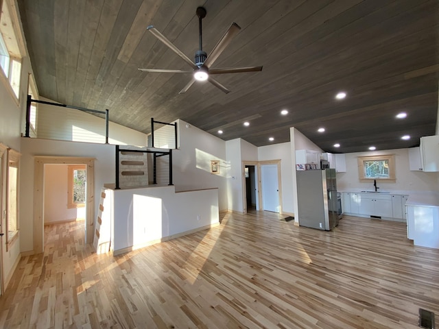 unfurnished living room featuring baseboards, wooden ceiling, light wood-style floors, and a sink