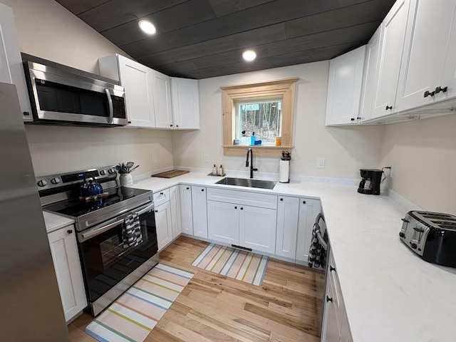 kitchen with appliances with stainless steel finishes, white cabinetry, and a sink