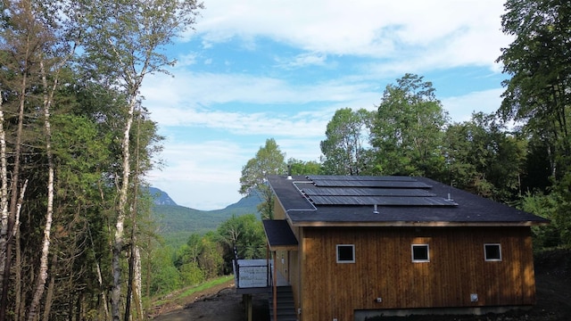 view of home's exterior featuring roof mounted solar panels and a mountain view
