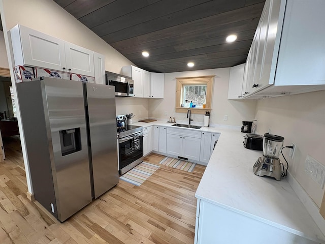 kitchen with light countertops, a sink, appliances with stainless steel finishes, and light wood-style floors