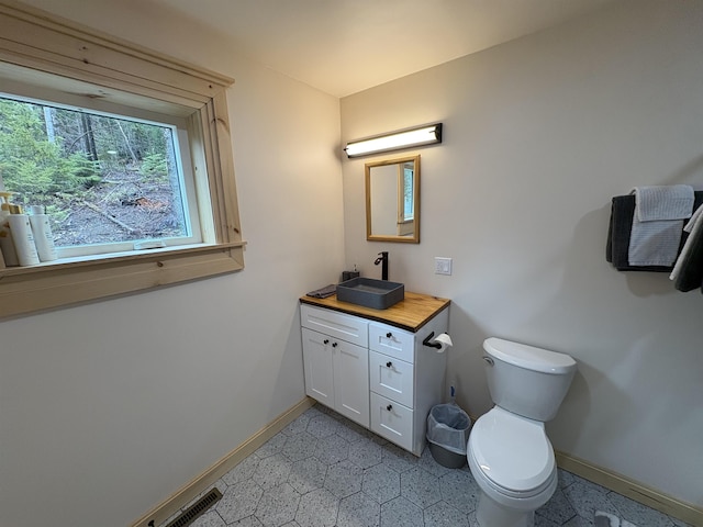 bathroom with vanity, toilet, visible vents, and baseboards