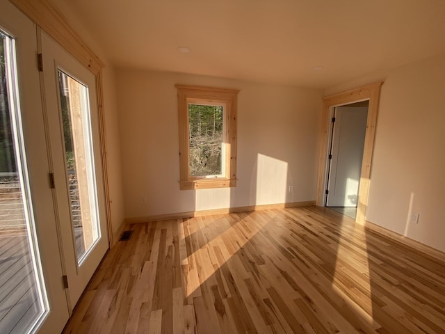 unfurnished room featuring visible vents, light wood-style flooring, and baseboards