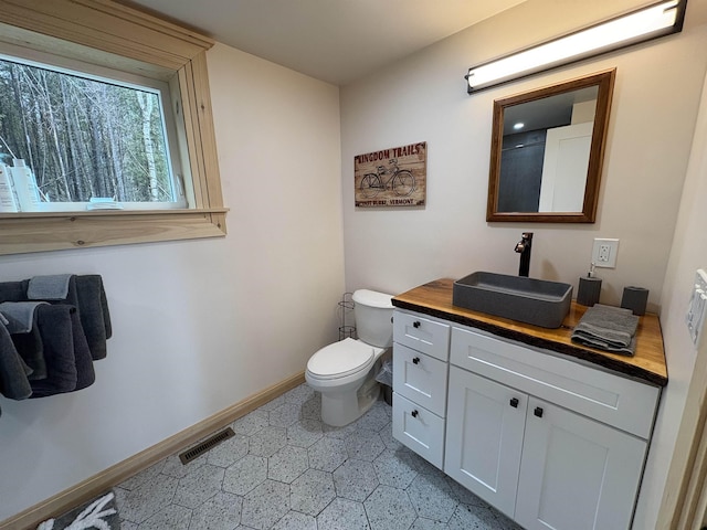 bathroom with baseboards, visible vents, toilet, and vanity