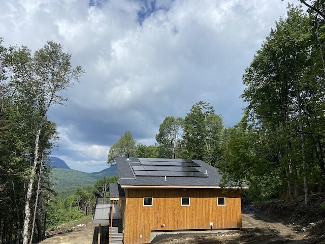view of outdoor structure with stairway, a mountain view, and solar panels