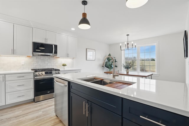 kitchen featuring white cabinets, stainless steel appliances, light countertops, and a sink