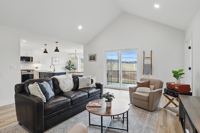 living area with recessed lighting, high vaulted ceiling, a chandelier, and light wood-type flooring