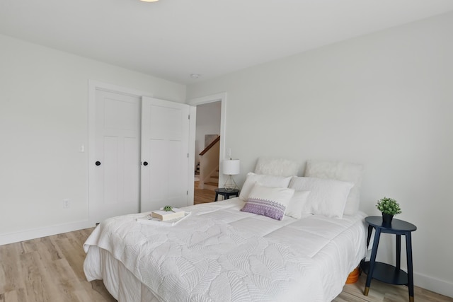 bedroom with light wood finished floors, a closet, and baseboards