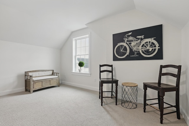 living area with carpet flooring, vaulted ceiling, and baseboards