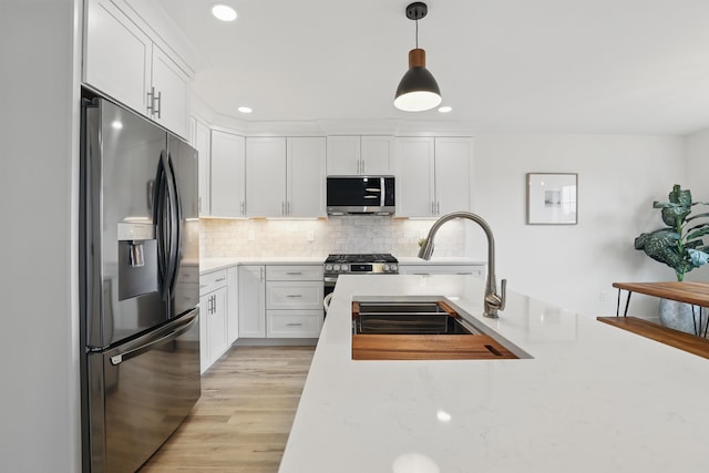 kitchen with white cabinets, stainless steel appliances, decorative backsplash, and a sink