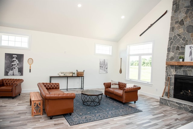 living area with a wealth of natural light, wood finished floors, high vaulted ceiling, and baseboards