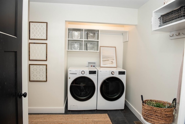 clothes washing area featuring dark tile patterned flooring, washer and dryer, laundry area, and baseboards