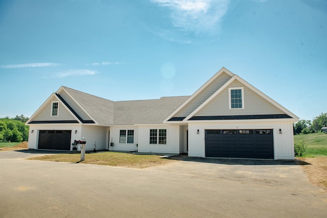 modern farmhouse with driveway, roof with shingles, and board and batten siding