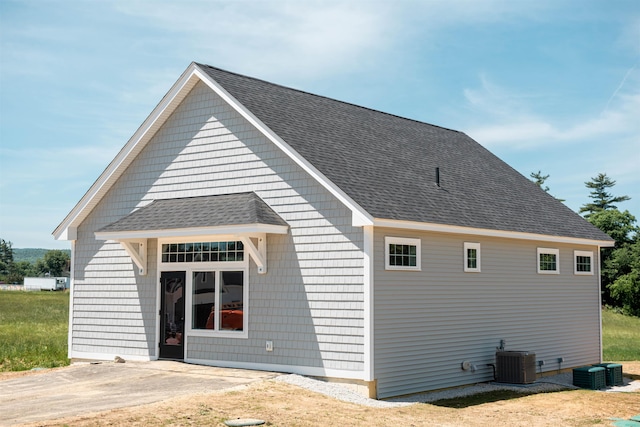 back of house with a shingled roof and central AC unit