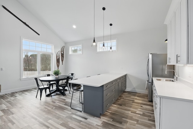 kitchen with a kitchen breakfast bar, gray cabinets, light wood-type flooring, a peninsula, and white cabinets