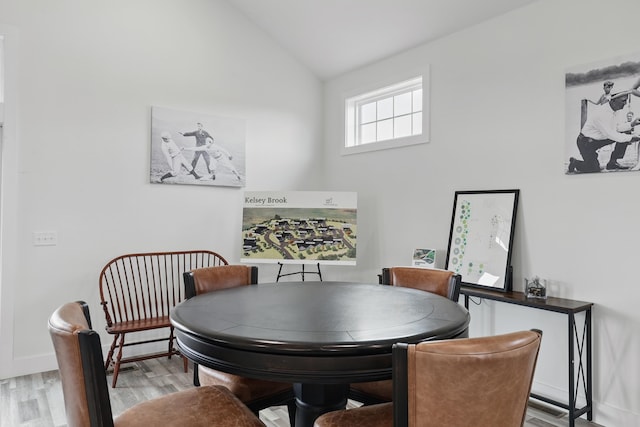 dining room featuring vaulted ceiling, light wood-style flooring, and baseboards