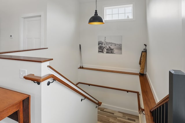 staircase featuring wood finished floors and baseboards