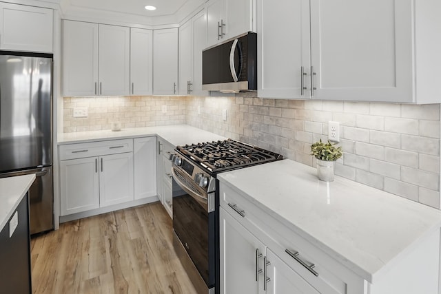 kitchen with tasteful backsplash, white cabinetry, stainless steel appliances, and light wood-style floors