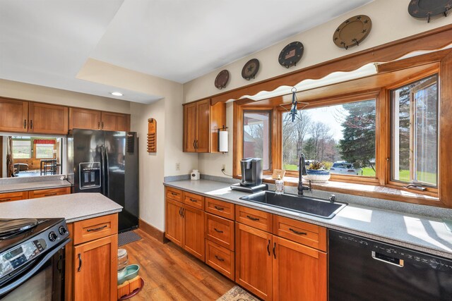 7449 School St, Loudon, NH 03307 - kitchen featuring wood finished floors, light countertops, brown cabinets, black appliances, and a sink