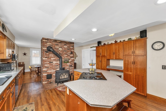 7449 School St, Loudon, NH 03307 - kitchen with brown cabinets, a wood stove, light countertops, a kitchen island, and dark wood-type flooring