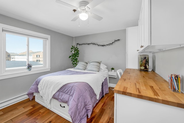 bedroom featuring a baseboard radiator, wood finished floors, and a ceiling fan
