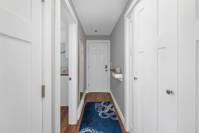 corridor featuring baseboards and wood finished floors