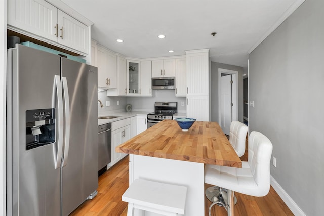 kitchen featuring recessed lighting, a sink, stainless steel appliances, light wood-type flooring, and white cabinets