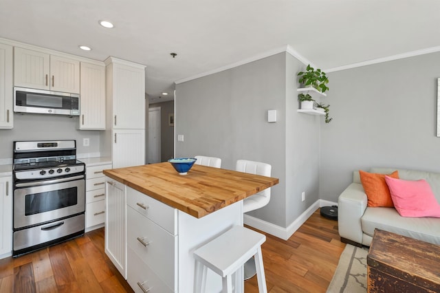 kitchen featuring wood counters, crown molding, stainless steel appliances, recessed lighting, and wood finished floors