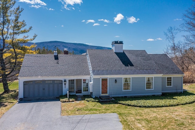 single story home featuring a chimney, a front lawn, driveway, and an attached garage