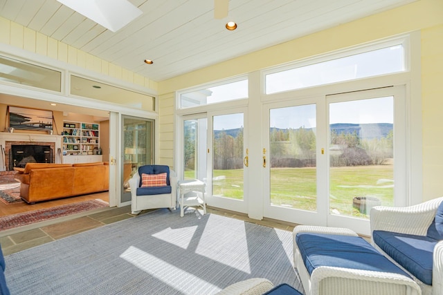 sunroom / solarium with a fireplace, a mountain view, a skylight, and plenty of natural light