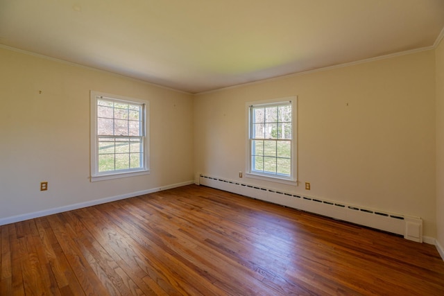 spare room with hardwood / wood-style floors, ornamental molding, plenty of natural light, and a baseboard radiator