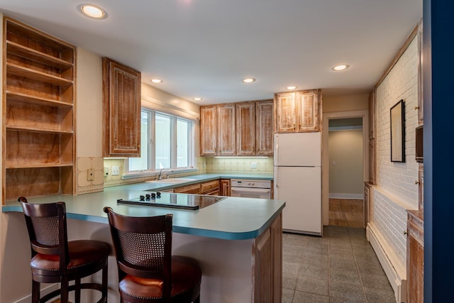 kitchen featuring recessed lighting, white appliances, a breakfast bar area, a sink, and a peninsula