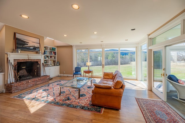 living area featuring a brick fireplace, wood finished floors, and plenty of natural light