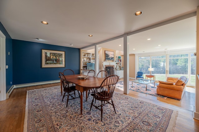 dining area featuring baseboard heating, recessed lighting, wood finished floors, and a fireplace