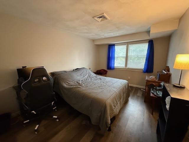 bedroom featuring wood finished floors, visible vents, and baseboards