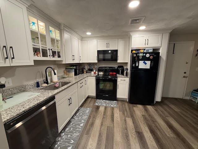 kitchen with a sink, black appliances, visible vents, and white cabinetry