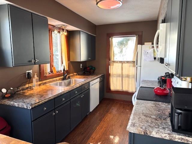 kitchen with white appliances, baseboards, a sink, and dark wood-type flooring