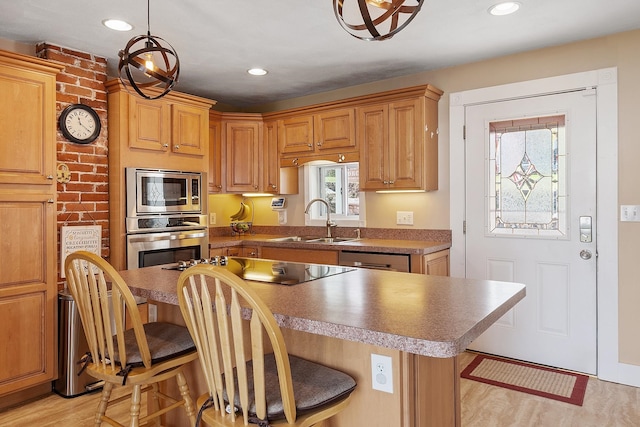 kitchen featuring light wood finished floors, a sink, a kitchen bar, a center island, and appliances with stainless steel finishes
