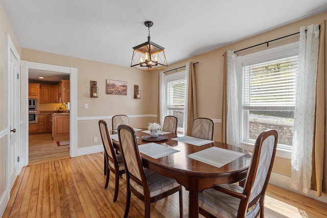 dining space with baseboards, a chandelier, and light wood-style floors