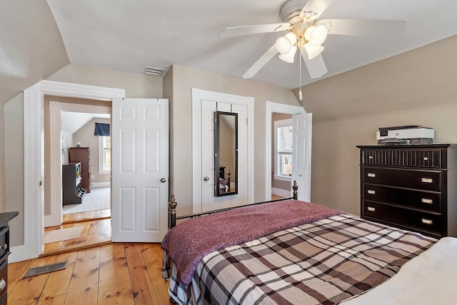 bedroom featuring visible vents, multiple windows, lofted ceiling, and light wood-style floors