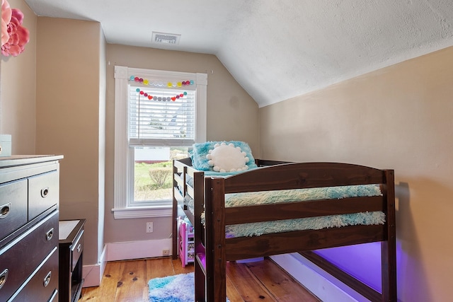 bedroom with visible vents, light wood finished floors, vaulted ceiling, and multiple windows
