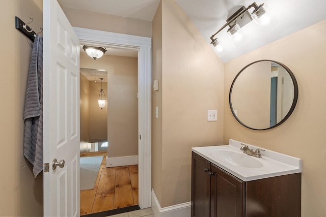 bathroom with wood finished floors, vanity, and baseboards