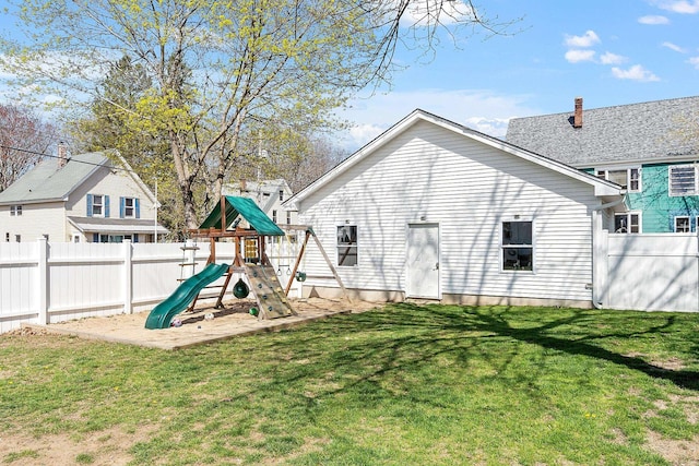 rear view of property with a yard, a playground, and fence